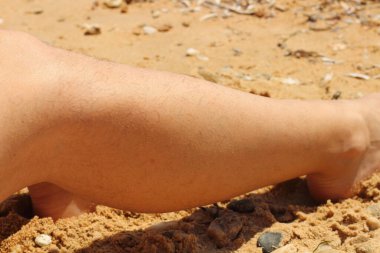 On a sun-drenched beach in Greece, a confident woman proudly displays her natural, hairy legs, embracing body positivity and challenging societal norms. clipart