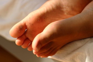 Resting on soft sheets, a pair of dirty feet bring a playful and relaxed vibe, suggesting a day well spent outdoors. The contrast between the dust-covered soles clipart