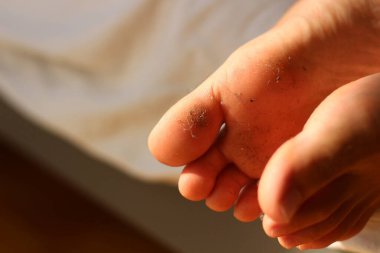 Yumuşak çarşafların üzerinde dinlenirken, bir çift kirli ayak neşeli ve rahat bir hava getiriyor, dışarıda iyi bir gün geçirildiğini gösteriyor. Toz kaplı tabanlar arasındaki zıtlık