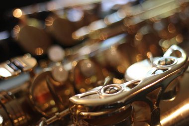 Alto saksafonun yakın planında, titreyen bokeh şekilleri arkada dans ediyor, enstrümanın kıvrımlarını vurguluyor.