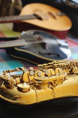 Alto saksafon ön planda zarif duruyor, arkasında bir buzlu içecek ve bir mandolin var.