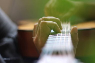 hrough the cut-outs of a monstera leaf, hands can be seen playing chords and melodies on the neck of an acoustic guitar clipart