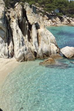 Yunanistan 'ın Halkidiki kentindeki el değmemiş bir plajın sakin dikey çekimi, kristal berrak turkuaz suları, yumuşak altın kum ve huzur dolu