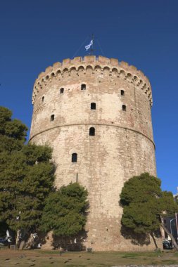 Yunanistan 'ın tarihi bir simgesi olan Selanik' in Beyaz Kulesi 'nin çarpıcı bir fotoğrafı, tabanı ağaçlarla çevrili açık mavi bir gökyüzünün altında çekildi.