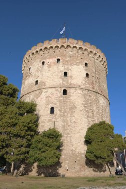 Yunanistan 'ın tarihi bir simgesi olan Selanik' in Beyaz Kulesi 'nin çarpıcı bir fotoğrafı, tabanı ağaçlarla çevrili açık mavi bir gökyüzünün altında çekildi.