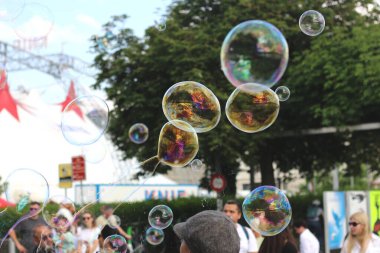 Zürih 'te zarif bir şekilde yüzen canlı, dev sabun köpüklerinin tuhaf bir görüntüsü narin, şeffaf yüzeylerinde göz kamaştırıcı gökkuşağı renklerini yansıtıyor.