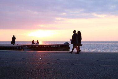 Selanik 'te gün batımında Nea Paralia boyunca el ele yürüyen bir çiftin romantik anı..