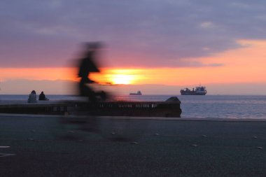 stunning long-exposure shot capturing the silhouette of a bicycle against the vibrant sunset at Nea Paralia in Thessaloniki clipart