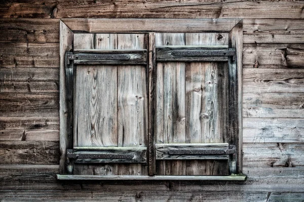 Closed creepy old and weathered wooden shutters on window of vintage hut, dark spooky style