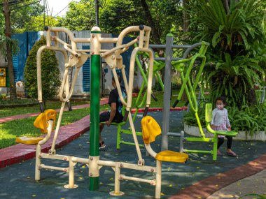 Two sets of colorful outdoor fitness equipment placed at a public park during a clear sunny morning.