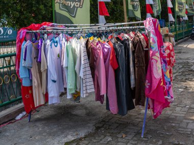 Banten, Indonesia - August 13, 2022: A clothesline with many laundry items hung using clothes hangers to be sun-dried on a bright sunny day.