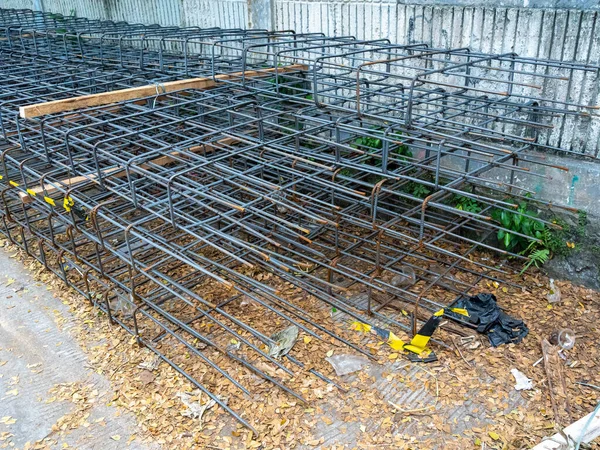 A series of column-shaped steel frames ready to use for civil construction and stacked on a concrete floor.