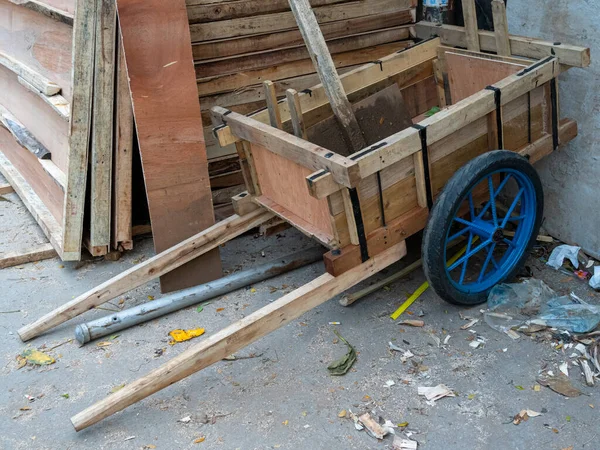 A freshly made wooden pull cart with blue wheels and black tires.