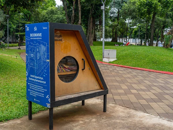 Jakarta, Indonesia - August 16, 2022: A trapezoidal book cupboard with blue back and circular window showing book content at a public park.
