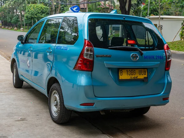 Jakarta, Indonesia - August 19, 2022: Rear view of a blue minivan taxi unit waiting for passengers on a sunny morning.