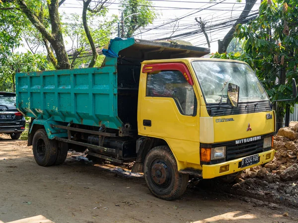 Banten, Indonesia - August 13, 2022: A common dump truck with yellow and green color combination parking at a civil construction area on a sunny morning.
