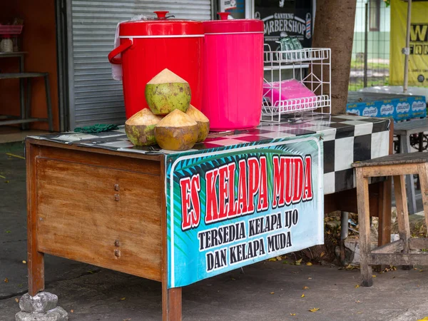 Banten, Indonesia - August 11, 2022: A common young coconut street vendor stall with large water and ice container and words saying 