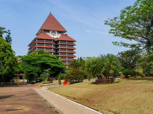 Depok, West Java, Indonesia - August 12, 2022: Landscape of the Center for Administrative Building of the University of Indonesia with foliage decoration and a leading line under clear blue sky.