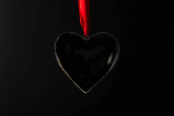 黒の背景に透明ハートペンダント 赤いリボン 上からの眺め バレンタインデー ストック写真