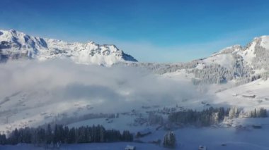 Great aerial footage in 4K of a wintry dream landscape in the Swiss mountains with a mystical mood because of the fog.