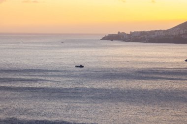 Amazing sunset over the Atlantic Ocean with a colorful horizon and a boat on the water.
