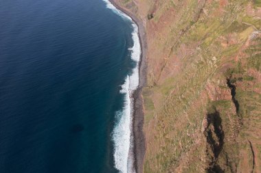 Great drone photo from a cliff on Madeira where a lighthouse stands at the forefront of the cliff warning ships about to land.