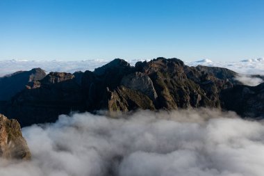 Epic mountain scenery on the small island of Madeira with a large sea of clouds behind the mountain peaks.