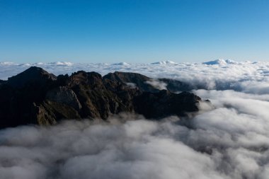 Epic mountain scenery on the small island of Madeira with a large sea of clouds behind the mountain peaks.