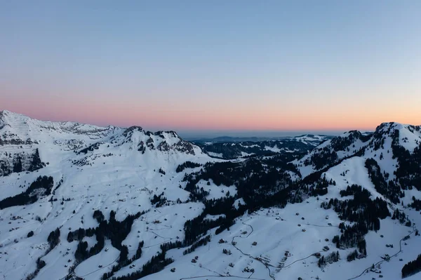 Great drone photo over the Swiss Alps at an epic sunrise with a pink horizon.