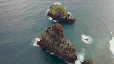 Aerial, orbit, drone footage of Ilheus da Rib costal arch, on Ribeira da Janela coast, foggy day, in Madeira, Portugal.