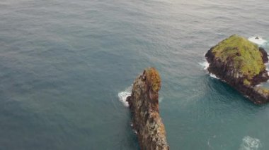 Aerial, orbit, drone footage of Ilheus da Rib costal arch, on Ribeira da Janela coast, foggy day, in Madeira, Portugal.