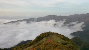 Awesome drone flight around a mountain in Madeira, Portugal. A great sunset with some wind mills in the background.