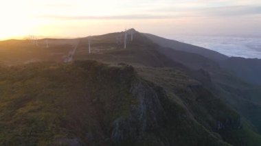 Epic drone flight over the Pica da Cana viewpoint in Madeira, Portugal. A wonderful sunset with several wind turbines in the background.