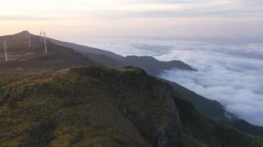 Epic drone flight over the Pica da Cana viewpoint in Madeira, Portugal. A wonderful sunset with several wind turbines in the background.