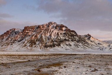 Beautiful landscape in Iceland in winter by a long and colorful sunrise with the mountains in the background.