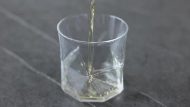 İki buz küpü viski dolu bir bardağa düşer ve dökülür..
