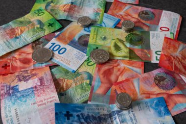 Birçok madeni para dağınık banknotların üzerinde yatar. İsviçre frangı çok güçlüdür ve İsviçre ekonomisi de iyidir..