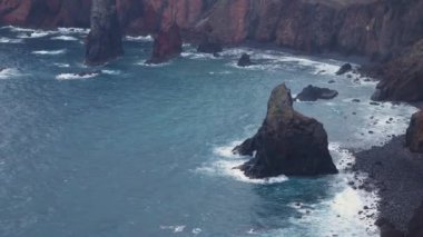 Madeira kıyısındaki yağmurlu bir günün 4K videosu dalgaların kırmızı volkanik kayalıklara çarptığı yer..