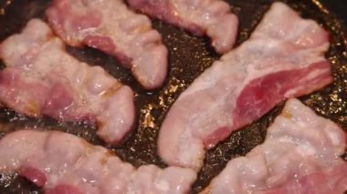 Bir şef biraz domuz pastırması kızartır ve pişene kadar düzenli olarak çevirir..