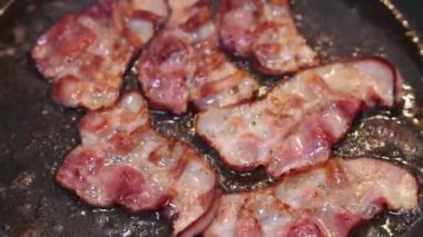 Bir şef biraz domuz pastırması kızartır ve pişene kadar düzenli olarak çevirir..