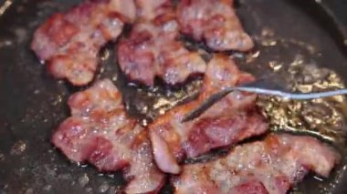 Bir şef biraz domuz pastırması kızartır ve pişene kadar düzenli olarak çevirir..