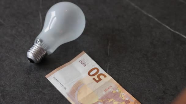Een Man Legt Meerdere Euro Tafel Naast Een Gloeilamp Elektriciteitsrekening — Stockvideo