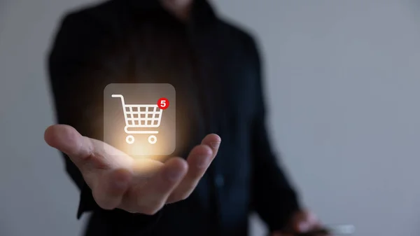 İş adamı online alışveriş kavramına sahip akıllı telefonu, online alışveriş arabasının sanal arayüzüne sahip pazar sitesi ağın bir parçası, alışveriş arabasının seçimiyle çevrimiçi alışveriş işi.