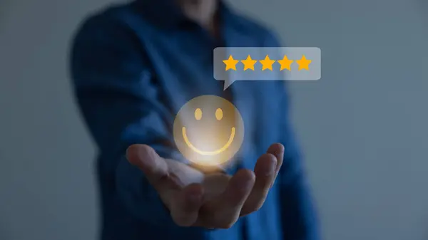Businessman using a mobile phone to point to a smile face and five stars icon, representing positive reviews and customer satisfaction. Building credibility and trust with happy customers.