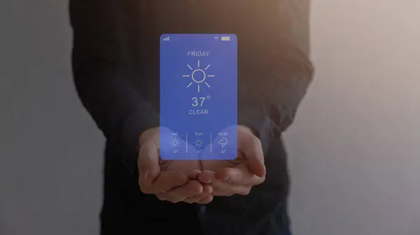 Weather forecast on smartphone. Weather forecast display app on Sunday, temperature, and sun, climate icons appear on virtual screen on mobile smart phone in stylish woman hands standing on the beach.