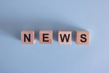 Beton yüzeyinde ahşap küp ve metin haberleri. Finans, yatırım, ekonomi. tasarım için sağdaki boşluğu kopyala, gri arkaplan.