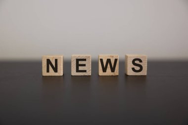 Beton yüzeyinde ahşap küp ve metin haberleri. Finans, yatırım, ekonomi. tasarım için sağdaki boşluğu kopyala, gri arkaplan.