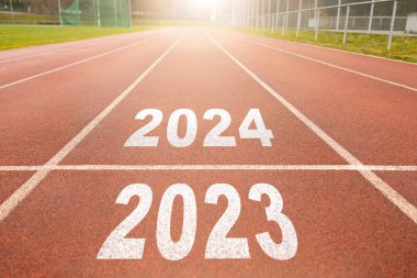 Mutlu yıllar 2024, yeni yılın başlangıcını simgeliyor. 2024 yılına kazınmış atletizm pistinde koşmaya hazırlanan bir adamın arka görünüşü. Başarının amacı. Yeni yıla hazırlanıyorum..