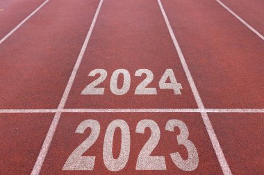 Mutlu yıllar 2024, yeni yılın başlangıcını simgeliyor. 2024 yılına kazınmış atletizm pistinde koşmaya hazırlanan bir adamın arka görünüşü. Başarının amacı. Yeni yıla hazırlanıyorum..