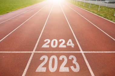 Mutlu yıllar 2024, yeni yılın başlangıcını simgeliyor. 2024 yılına kazınmış atletizm pistinde koşmaya hazırlanan bir adamın arka görünüşü. Başarının amacı. Yeni yıla hazırlanıyorum..